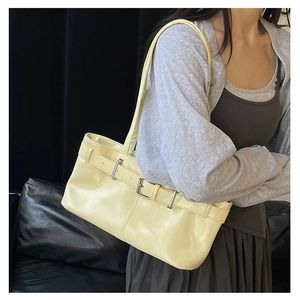 Detail of yellow glossy leather shoulder bag with decorative belt and silver buckle