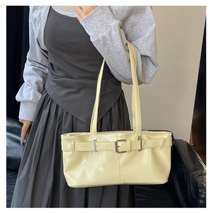 Close-up of a cream-colored baguette shoulder bag with stylish metal buckle detailing