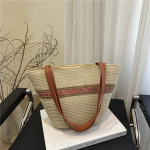 Minimalist woven straw bucket bag with vibrant wavy pattern and brown leather straps