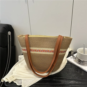 Handwoven straw bucket bag with brown leather straps and colorful striped accents