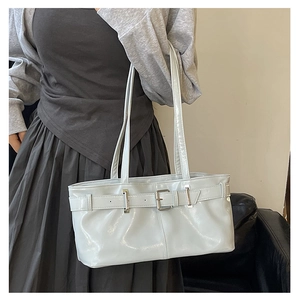 Close-up of a grey glossy patent leather baguette bag with strap buckle detail