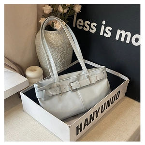 Detail of light blue glossy patent leather baguette bag with metal buckle and dual straps