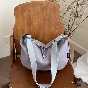 Minimalist lavender nylon crescent tote bag on a wooden chair with a wide woven strap