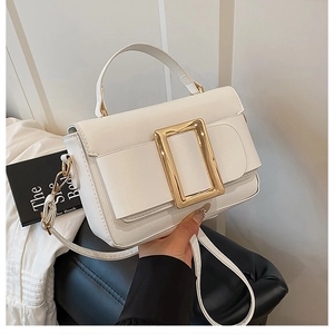 Detail of white PU leather crossbody bag featuring a signature gold buckle and bow flap