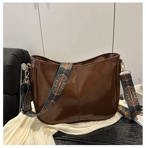 Detail of glossy brown crossbody bag with bohemian patterned wide shoulder strap