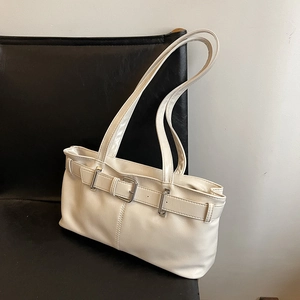 Minimalist white PU leather baguette bag with metal buckle detail on a black leather seat