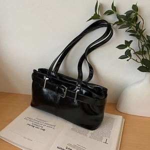 Minimalist black glossy baguette bag with silver buckle on a stylish magazine