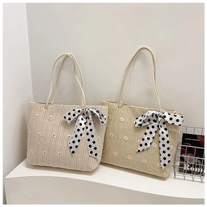 Détails de sacs cabas en paille brodés de marguerites avec nœuds à pois élégants