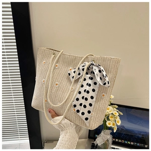 Detailed close-up of woven tote bag with daisy embroidery and polka dot ribbon