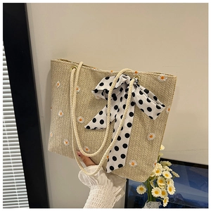 Detail of beige woven tote bag with daisy embroidery and polka dot bow handle scarf