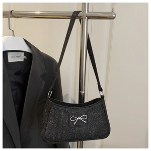 Detail der schwarzen Glitzer-Schultertasche mit silberner Metallschleife am Kleiderbügel
