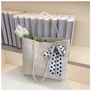 Detail of daisy embroidery and polka dot bow on woven tote bag with rope handle
