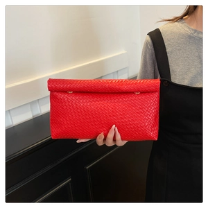Detail view of red woven leather clutch with dual gold rings and quilted texture