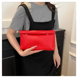 Detailed view of red woven envelope clutch bag with elegant golden metallic buckle closure