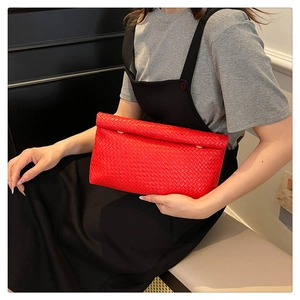 Detail of red woven leather clutch bag with golden metallic closures and folding design