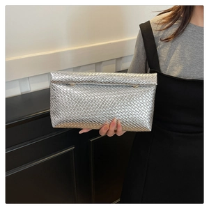 Macro detail of silver woven texture and metallic finish on a minimalist clutch bag