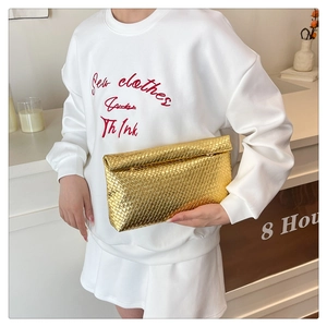 Detail shot of golden woven envelope clutch bag with premium metallic leather texture