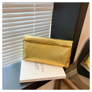 Close-up of golden woven clutch bag texture with elegant lighting on white book