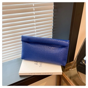 Detailed view of royal blue woven texture and flap closure on a stylish clutch bag