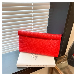 Macro view of red woven leather texture and metal buckle on the minimalist clutch bag