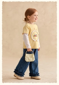 Detail of girls yellow layered cat tee and polka dot wide-leg pants with ruffle hem