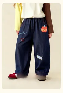 Detail of kids denim trousers with elastic waist and cute apple embroidery on leg