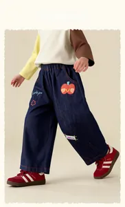 Detail of kids denim pants featuring cute apple patches and thank you embroidery
