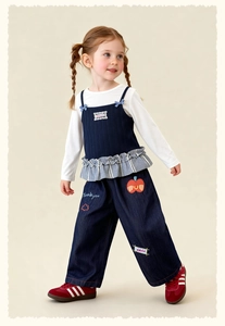 Detail of girls' casual outfit with striped vest and embroidered denim wide-leg pants
