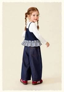 Detailed view of children's navy vest with ruffle hem and dark denim wide-leg trousers