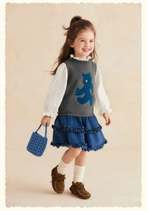 Gros plan d'un gilet en tricot gris avec un motif de petit ours bleu en dessin animé