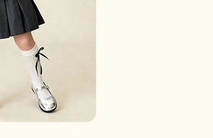 Close-up of white cotton girl socks with black ribbon bow and silver Mary Jane shoes