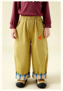 Close-up of mustard yellow cargo pants with squirrel embroidery and plaid cuff details