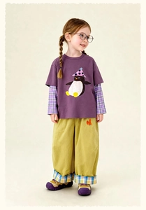 Child in purple penguin tee, plaid shirt layer and mustard yellow wide-leg trousers