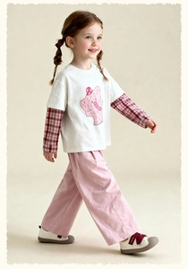Girl in casual wide-leg pink pants and a layered elephant print top in a studio setting