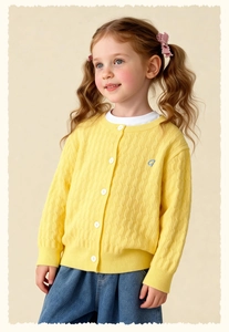 Detail of yellow cable-knit girls' cardigan featuring white buttons and blue embroidery