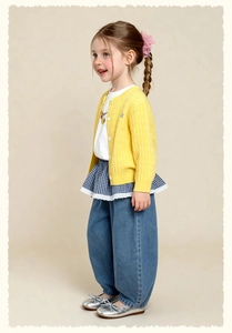 Detail of yellow knit cardigan with letter a embroidery over blue denim pants and silver shoes