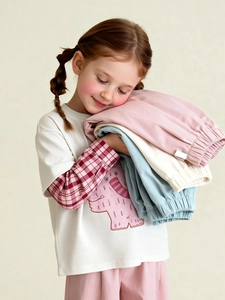 Kids spring casual wide-leg pants in pastel colors held by a smiling young model