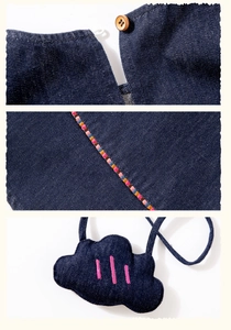 Detail of denim shirt with lace collar, wooden button, and cloud embroidery