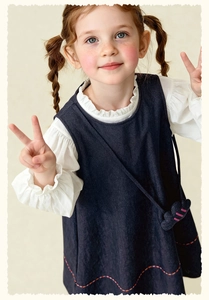 Detail of white cotton shirt featuring ruffled lace collar and navy denim vest dress