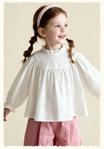 Detailed close-up of white long sleeve cotton shirt with ruffle collar and pleated chest
