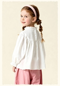 Detail of girls' white ruffle collar top with back button closure and textured cotton fabric