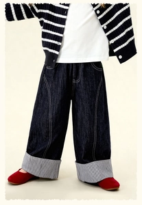 Détail d'un jean large pour fille avec revers élégants à rayures noires et blanches