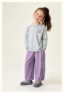 Detail van een kinderoutfit met blauwe bedrukte top en paarse cargo broek voor spel