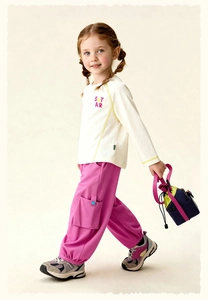 Detail van wit meisjessweatshirt met STAR-motief en roze cargo joggingbroek