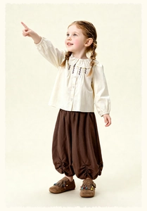Detail view of children's cotton pants featuring ruffle lace edges and pleated hem design