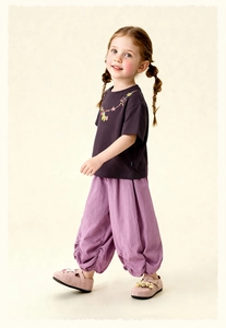 Detail of girls casual outfit with floral embroidery neckline and pleated cuffed pants