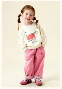 Detail showing girls' off-white cartoon elephant sweatshirt and pink trousers with plaid cuffs