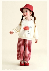 Detail of girls' beige crewneck sweatshirt with elephant print and plaid trousers