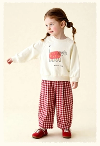 Detail of cream sweatshirt with elephant print and red checkered wide-leg pants for girls