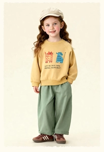Detail of yellow kids sweatshirt with cartoon cat and dog print and wide-leg green pants